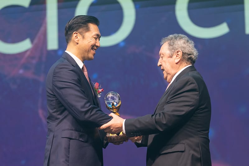 At the Global Peace Convention, a man in a suit is shaking hands with another distinguished individual at the Awards Gala.